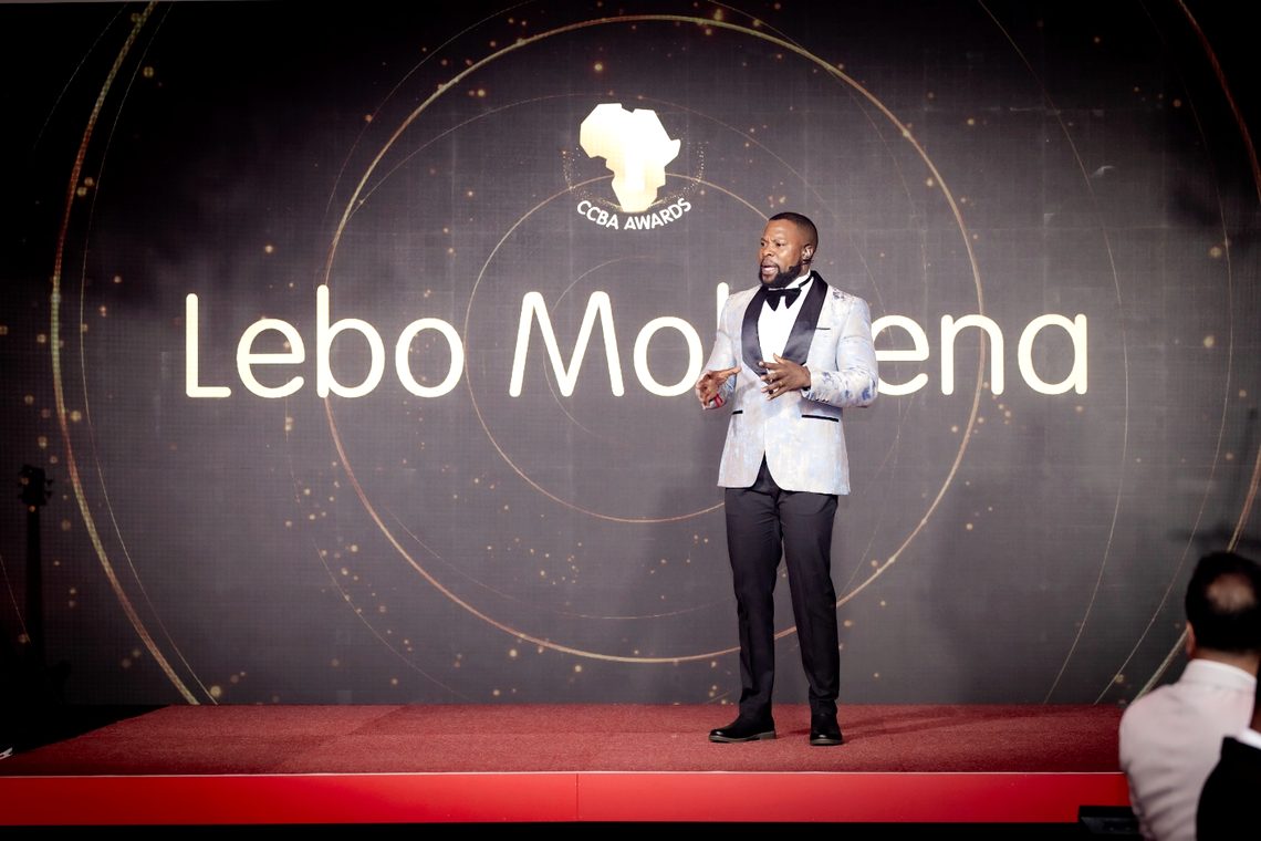 His name on the screen behind him at an awards evening